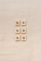 ho ho ho wooden letters on a beige knitted background texture