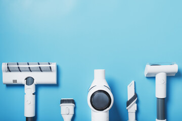 Composition of a set of elements of a wireless white vacuum cleaner on a blue background. Top view