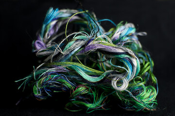 Tangled skein of colored threads on a black background.