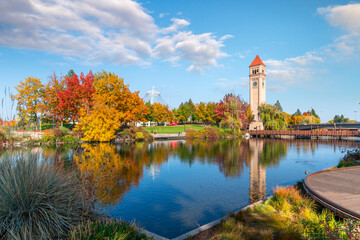 Autumn view of the clock tower and Expo Pavilion along the Spokane River at Riverfront Park in downtown Spokane, Washington, USA, with colorful leaves turning red and yellow.