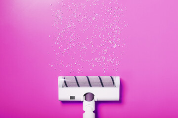 A white vacuum cleaner brush on a pink background.