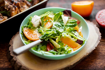 Healthy salad of fresh vegetables, herbs and tomatoes on a wooden background.
