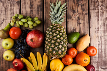 Mix of fresh juicy colorful exotic tropical fruits on wooden background top view