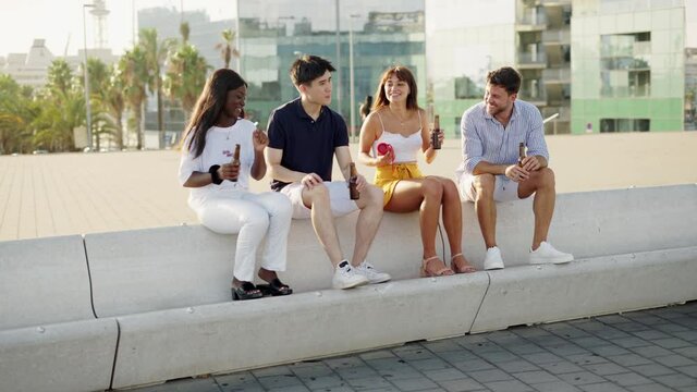 Happy Friends Of Different Races Listening Music On Portable Wireless Bluetooth Speaker Outdoors