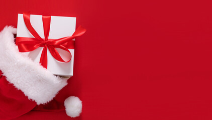 gift box in a hat santa claus on a red background top view with place for text