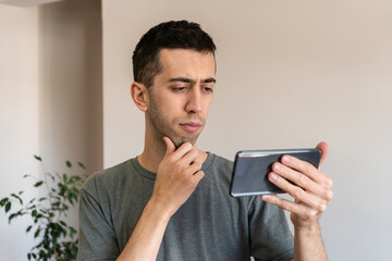 Man looking at his mobile phone with a thoughtful face