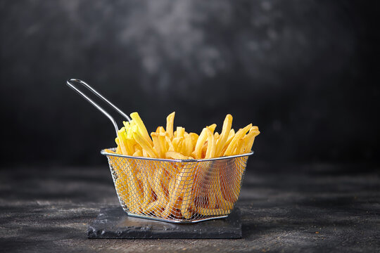 French fries in fryer basket on dark background