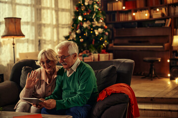 Senior couple celebrating Christmas with family via tablet