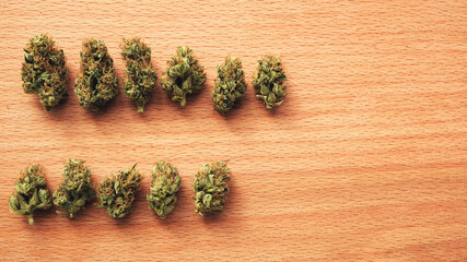Marijuana outdoor wild buds in row on wooden background. Top view, close-up. Cannabis dried...