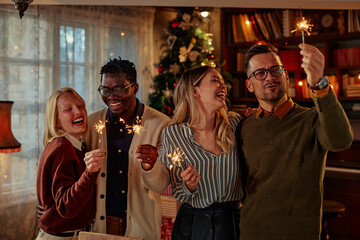 Diverse group of young friends having fun with sparklers at a party at home