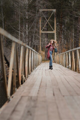 Young woman walking with ukulele guitar in bridge in autumn forest