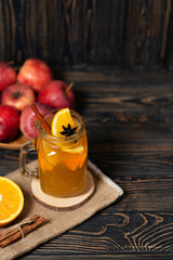 Hot apple honey punch or cider on dark wood background. Traditional fall or winter warming spicy beverage with cinnamon, star anise, orange. Homemade non-alcoholic drink recipe idea