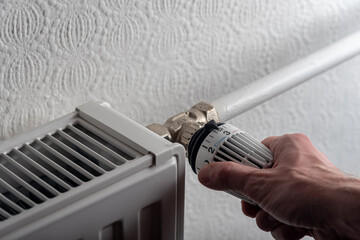 male hand adjusting knob of heating radiator