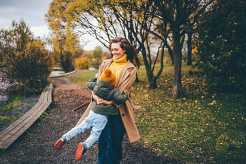 Mother and little daughter playing in an autumn park. 