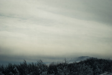 Melancholic weather. Ccloud covered sky over a mounatin landscape. Winter in the mountains.
