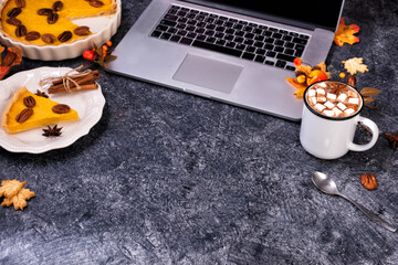 Workspace with laptop and Hot chocolate and homemade pumpkin pie with cinnamon and pecan nuts....