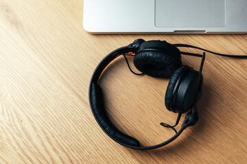 Black headphones and laptop on wooden background.