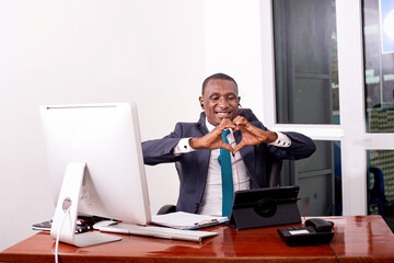 happy businessman during a video call on a digital tablet making a heart shape with his fingers.