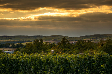 beautiful view of the sunset in southern moravia near the town of perna, czech republic, sunset over the town, cloudy sky, sunbeams breaking through the clouds