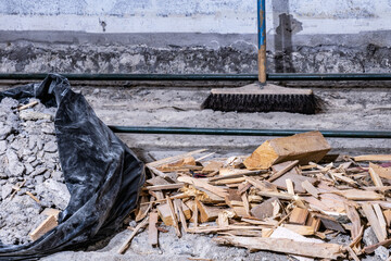 Construction waste debris in black plastic bag and on old concrete floor, from demolished room,...