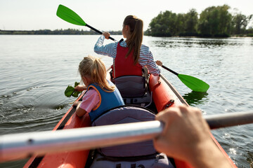 Family floating on kayak in lake or river at daytime