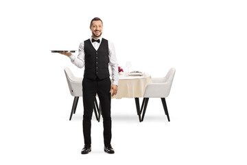 Full length portrait of a server with a silver tray standing in front of a restaurant table
