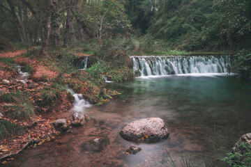 Forest in autumn with long exposure waterfall in bejis, valencia. Brown, green