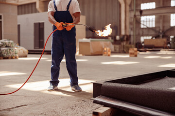 Male builder using gas burner at construction site