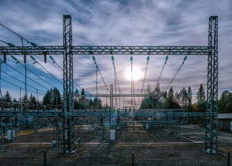 High voltage power transformer substation - wires with Sun at background, panorama view