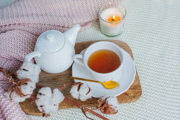 Autumn flat lay. Orange knitted pullover, hot cup of tea, candle light, wooden stand, cotton branch, pumpkin.
