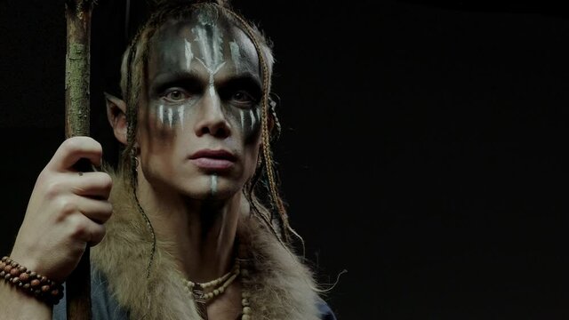 Handsome elf shaman talks and looks into camera on black