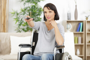young woman in wheelchair watching with remote control