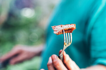Man offering a piece of meat roasted with a fork.
