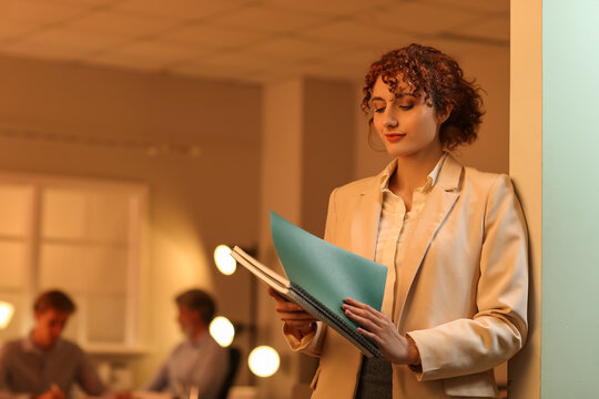 Young female worker with documents in office at night