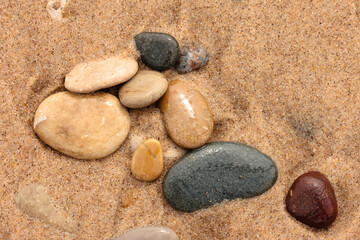 Fototapeta na wymiar A mix of stones recently washed by the waves of Lake Michigan, settle into the sand on the beach at Kohler-Andrae State Park, Sheboygan, Wisconsin