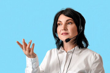 Mature female consultant of call center in headset on blue background