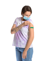 Young woman with medical mask and plaster onto her arm on white background