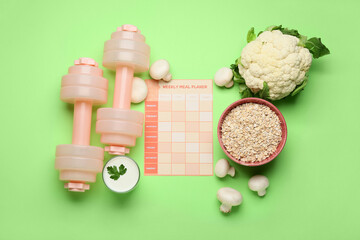 Meal plan with healthy products and dumbbells on green background