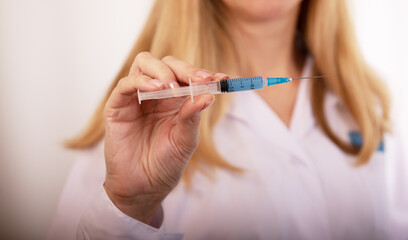 А nurse on a white background holds a syringe with a coronavirus vaccine