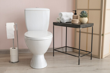 Modern bathroom with toilet paper holder and table with accessories