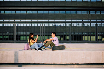 Fototapeta na wymiar A happy teenage couple is sitting at the train station and taking photos.