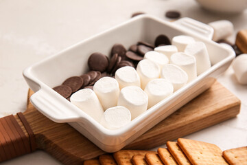 Baking dish with uncooked S'mores dip on light background, closeup