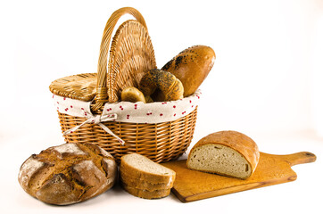 Basket with bread and whole wheat bread on white background. Sliced bread on board