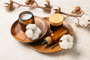 Composition with cosmetic products and cotton branch on light tile