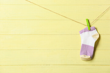 Pair of socks hanging on rope against yellow wooden background