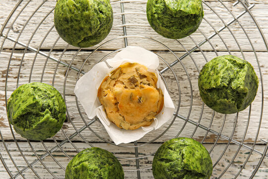 Grid with tasty spinach muffins on light wooden background