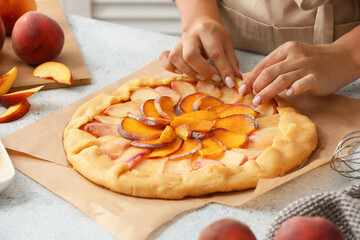 Woman preparing peach galette at table