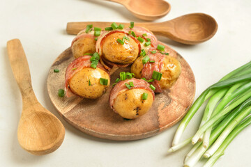 Plate of tasty baked potatoes with bacon on light background