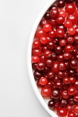 Bowl of tasty fresh cranberries on light background, closeup