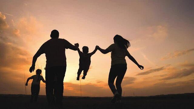 Happy Family. Parent A Baby Together Run In The Park At Sunset Silhouette. People In The Park Concept. Mom Dad Daughter And Son Joyful Run. Happy Family Fun And Baby Child Summer Kid Dream Concept